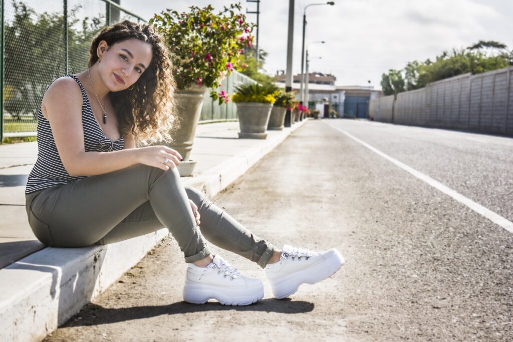 Conforto e performance nos tênis casuais 7 Mulher sentada com seu tênis branco