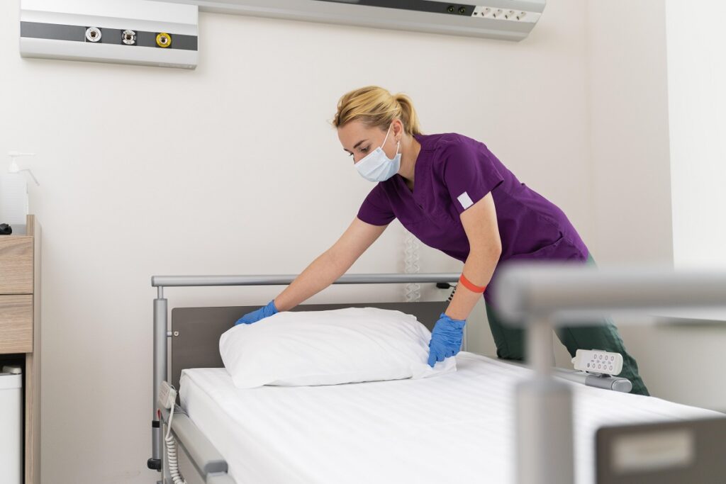 Enfermeira arrumando cama de hospital